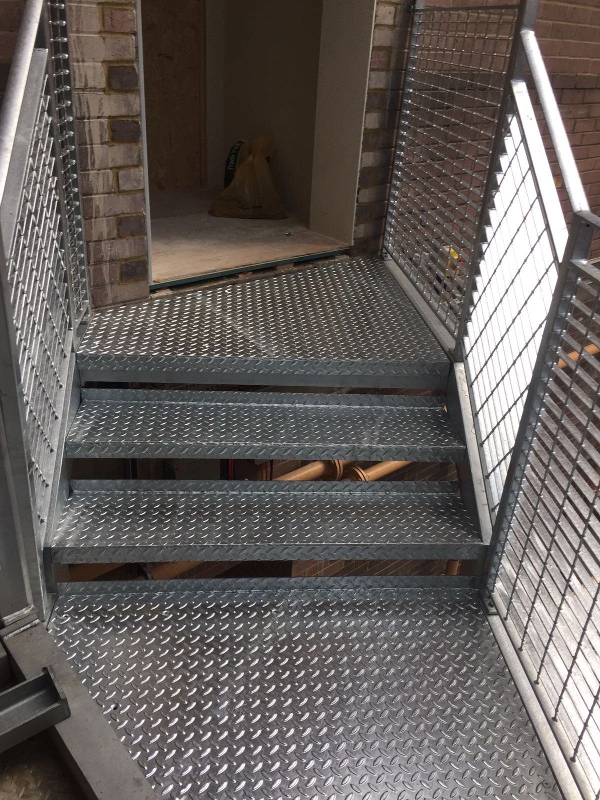 Galvanised steel staircase with chequer plate treads in a lightwell