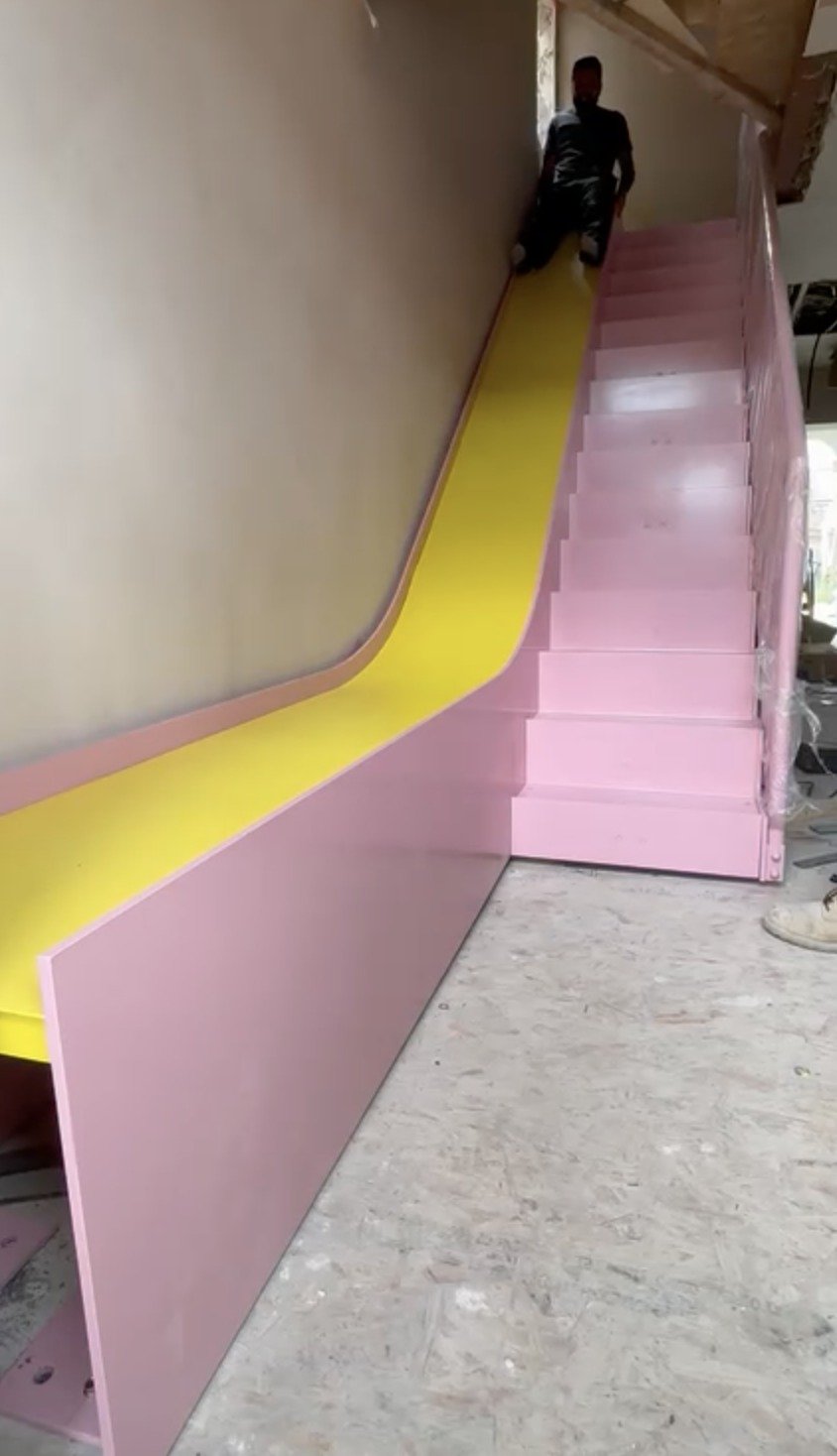 Pink powder-coated steel feature staircase with a yellow slide running alongside the flight