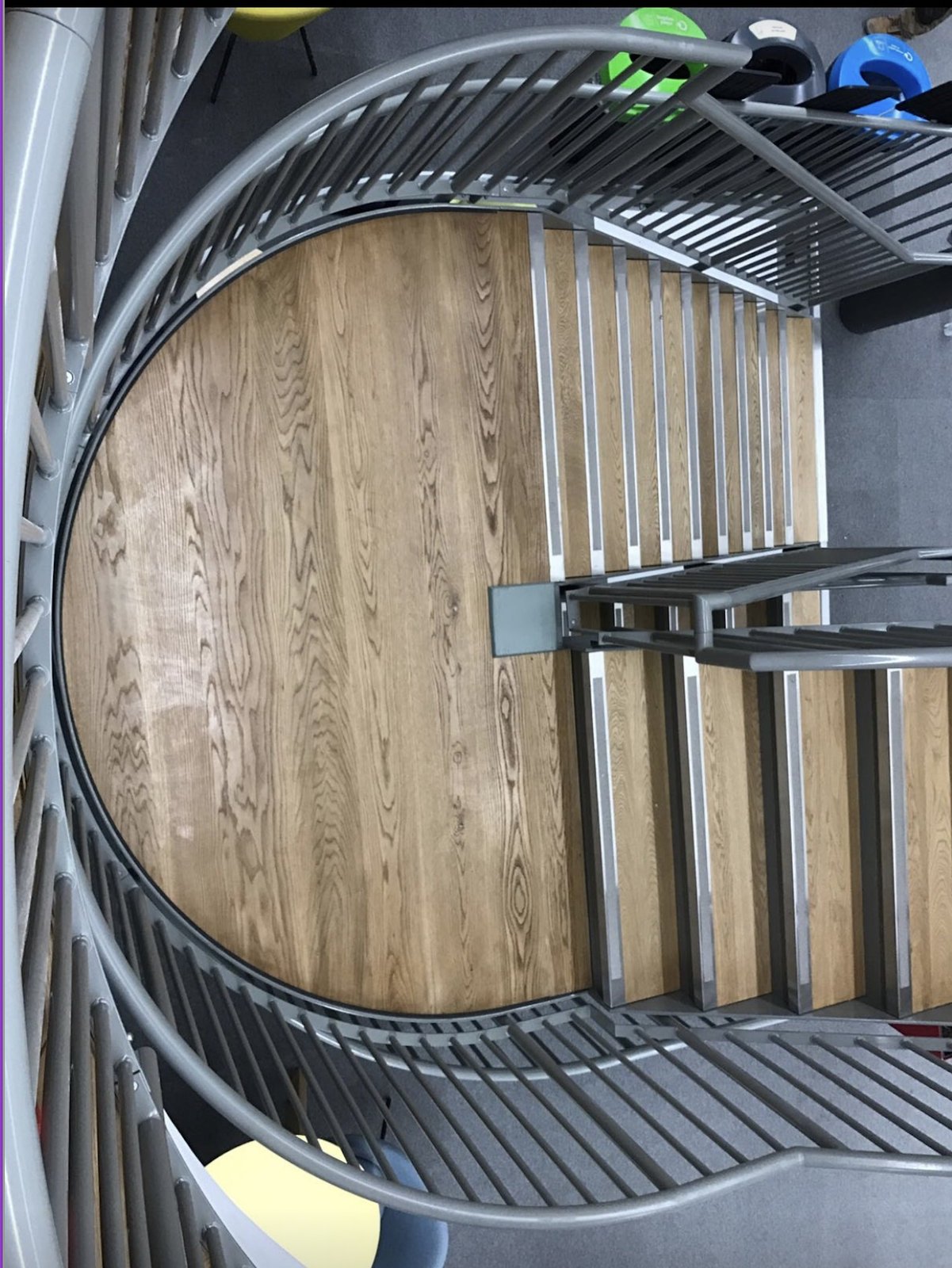 Steel spiral staircase with oak treads and vertical bar balustrade seen looking down from the top